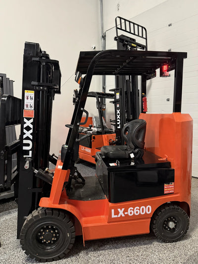 Rear three-quarter view of the LUXX LX-6600 Compact forklift revealing the ergonomic seat, red tail lights, overhead guard, and black mast in a multi-unit showroom.