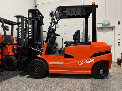 Full side profile of the LUXX LX-6600 orange forklift with amber beacon light, wide overhead guard, open operator cabin, and large solid tyres in an indoor showroom.